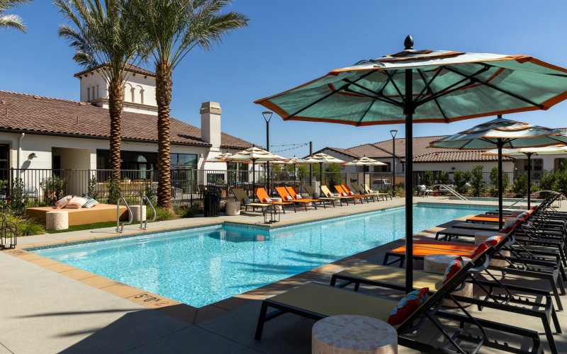 a swimming pool with lounge chairs and umbrellas next to a building