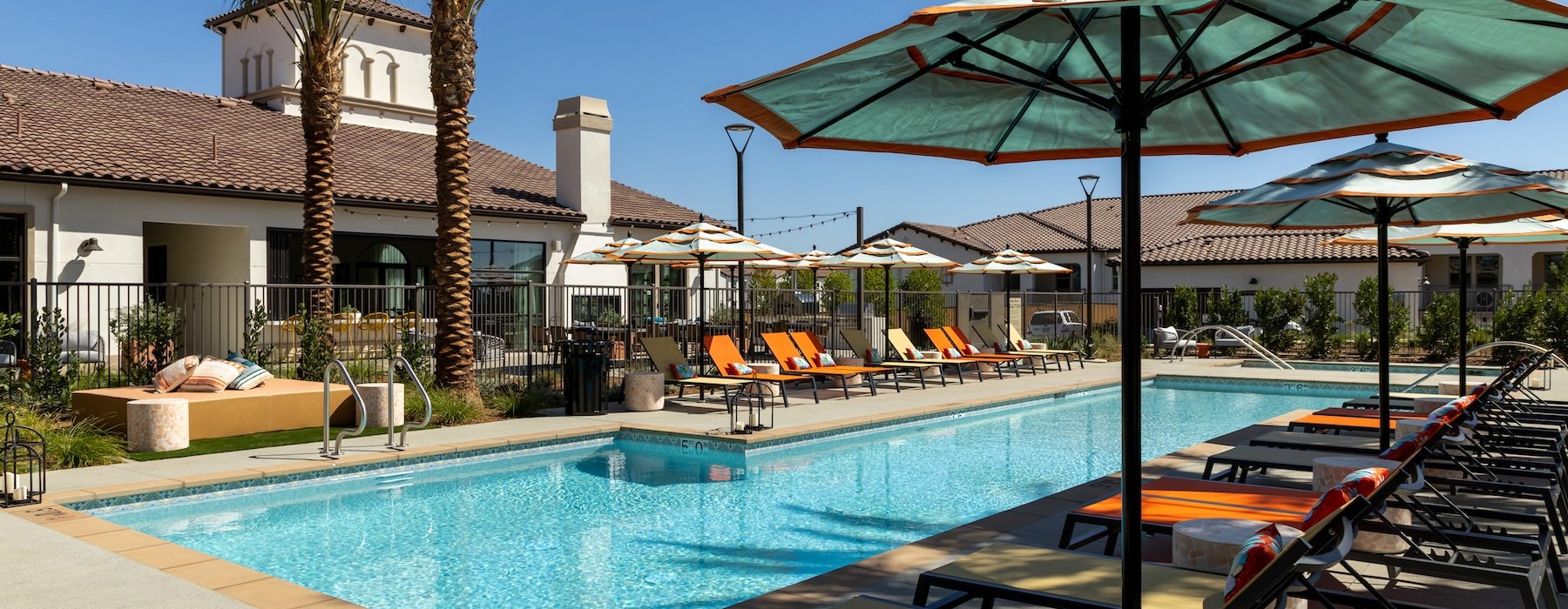 a swimming pool with lounge chairs and umbrellas next to a building