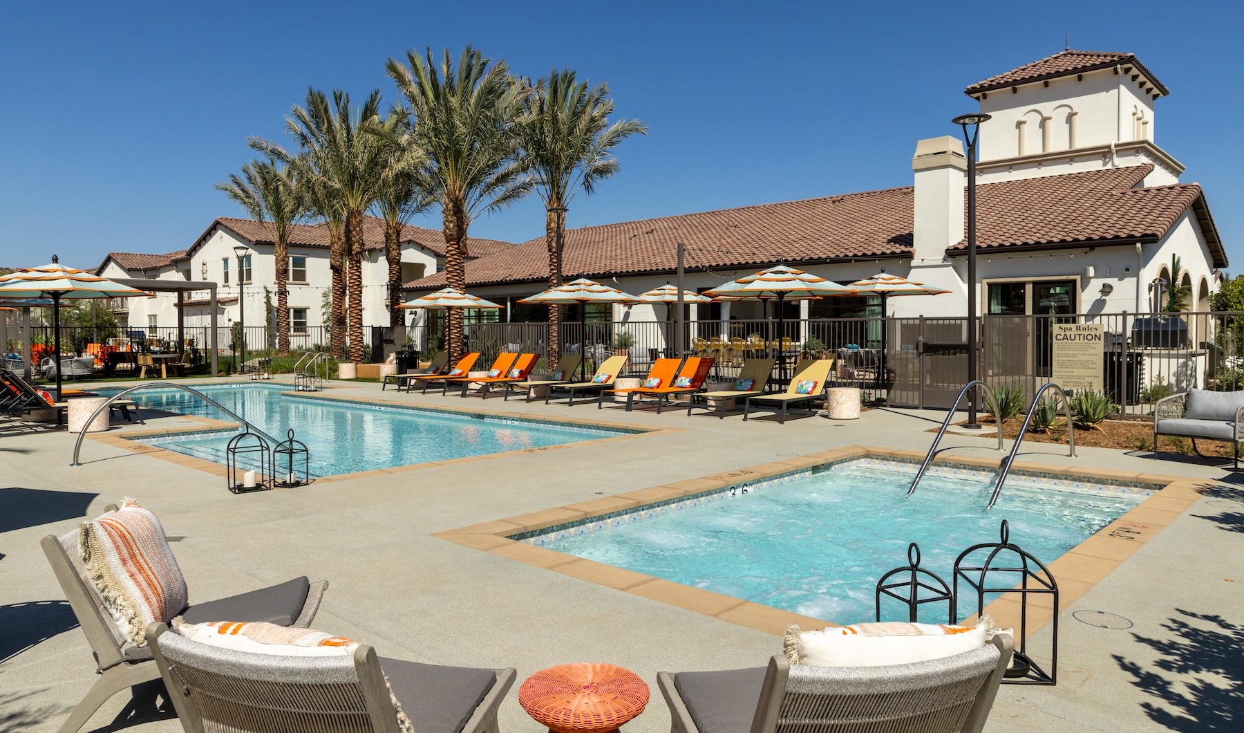 a swimming pool with lounge chairs and umbrellas next to a building