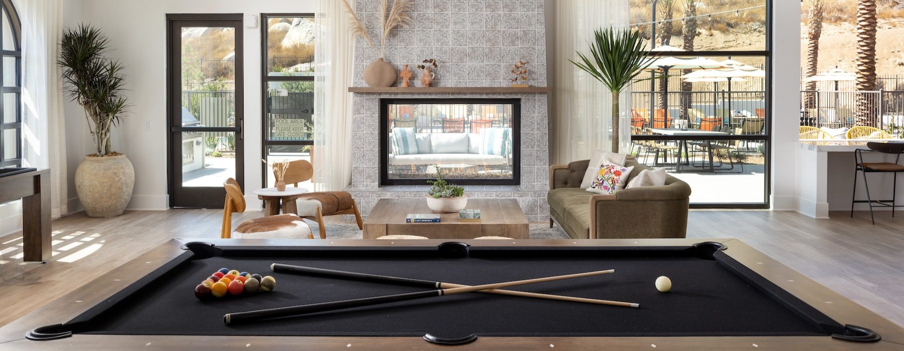 pool table in social room with a fireplace and large windows